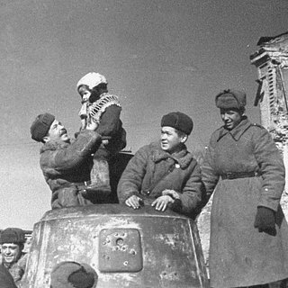 Советский солдат держит на руках ребенка в освобожденной Вязьме, март 1943 года