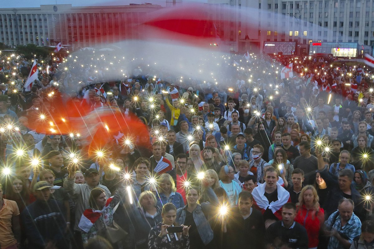 Сторонники оппозиции размахивают фонариками и бело-красно-белыми флагами во время акции протеста перед зданием правительства на площади Независимости в Минске, 19 августа 2020 года