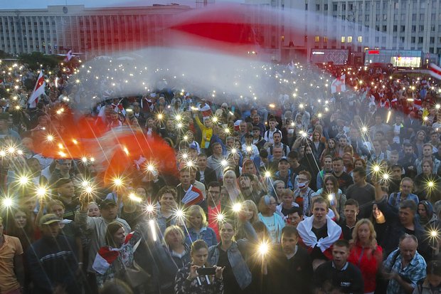 Сторонники оппозиции размахивают фонариками и бело-красно-белыми флагами во время акции протеста перед зданием правительства на площади Независимости в Минске, 19 августа 2020 года. Фото: Dmitri Lovetsky / AP