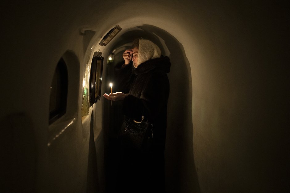 Женщина молится перед иконой в катакомбах Киево-Печерской лавры, 5 февраля 2023 года