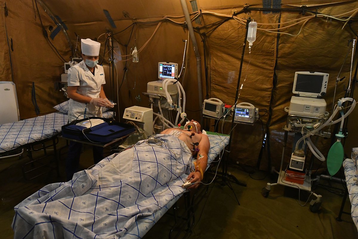 Медик проводит электрокардиографию пациенту в палатке полевого госпиталя в зоне специальной военной операции на Украине