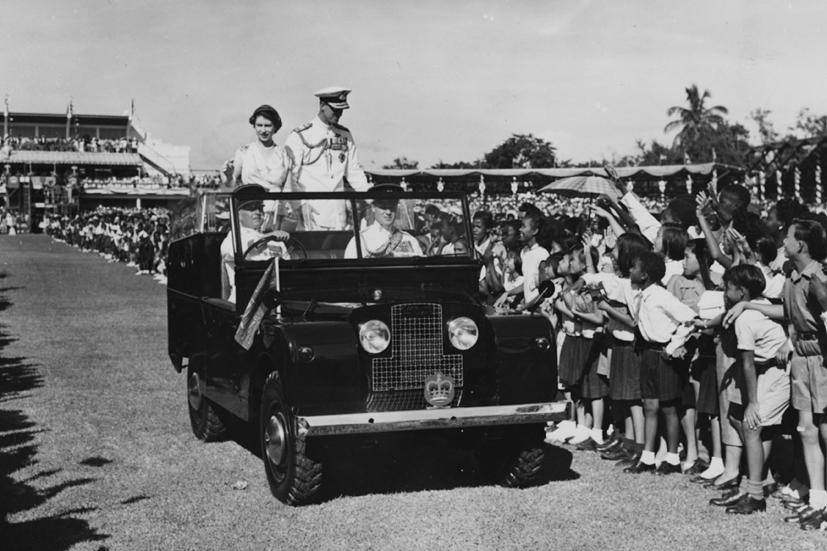 Королева Елизавета II и принц Филипп, герцог Эдинбургский, из открытого Land Rover приветствуют участников детского митинга в парке Сабина, Кингстон, Ямайка, ноябрь 1953 года