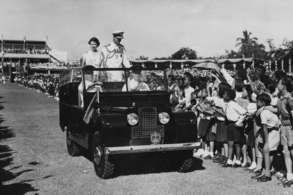 Королева Елизавета II и принц Филипп, герцог Эдинбургский, из открытого Land Rover приветствуют участников детского митинга в парке Сабина, Кингстон, Ямайка, ноябрь 1953 года