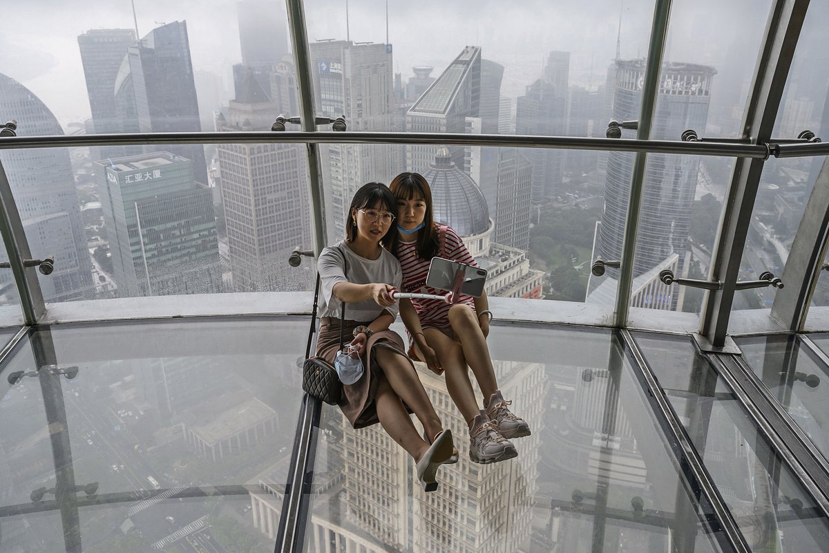 Девушки на стеклянной смотровой площадке телебашни «Восточная жемчужина» с видом на реку Хуанпу в Шанхае. 29 августа 2020 года