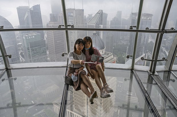Девушки на стеклянной смотровой площадке телебашни «Восточная жемчужина» с видом на реку Хуанпу в Шанхае. 29 августа 2020 года. Фото: Kevin Frayer / Getty Images