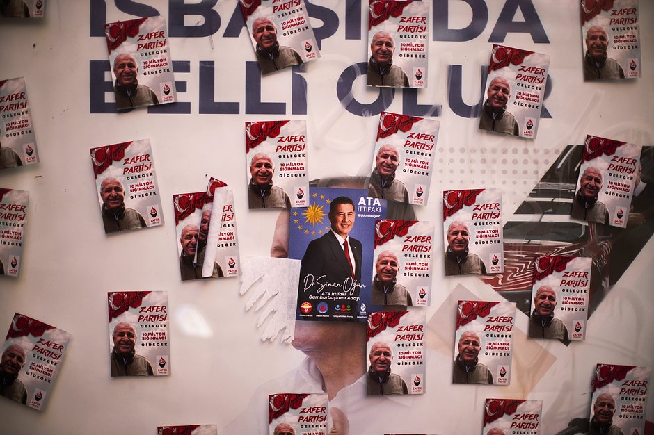 Наклейки с изображением кандидата в президенты Синана Огана (в центре на синем фоне) и его партнера по коалиции Умита Оздага на уличном рекламном щите в Стамбуле, Турция, 8 мая 2023 года