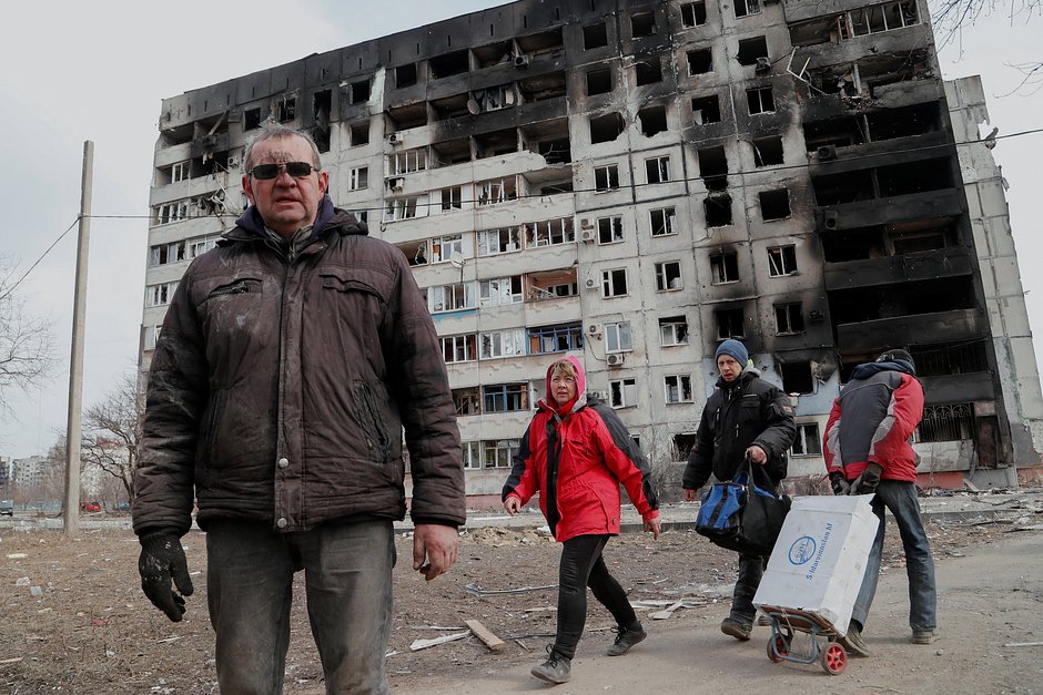 Люди возле многоквартирного дома, разрушенного во время боевых действий. Мариуполь, 17 марта 2022 года