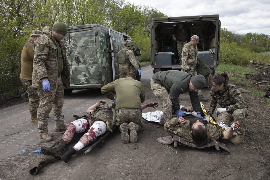Военные медики оказывают первую помощь раненым украинским солдатам на дороге возле Бахмута, 11 мая