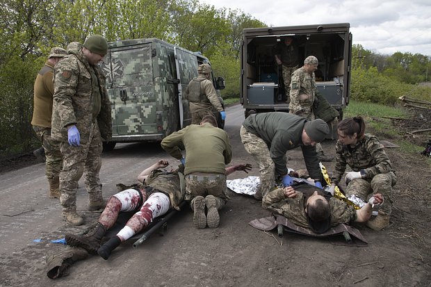Военные медики оказывают первую помощь раненым украинским солдатам на дороге возле Бахмута, 11 мая. Фото: Boghdan Kutiepov / AP