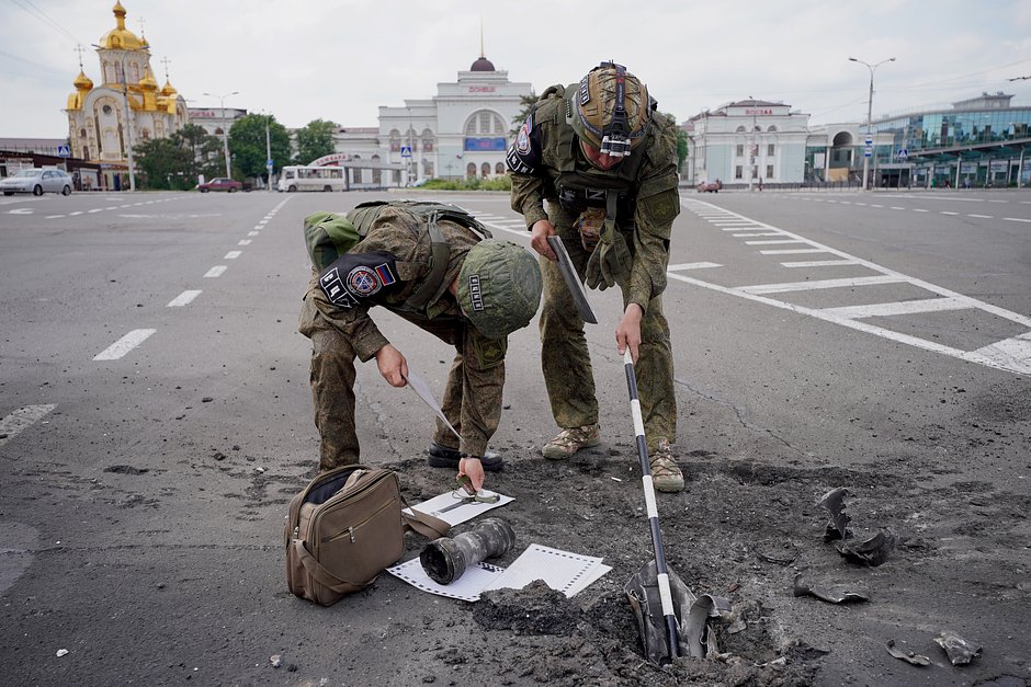 Сотрудники Совместного центра контроля и координации на месте попадания снаряда после обстрела Киевского района Донецка, 12 июня 2023 года