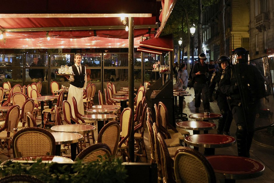 Полицейские проходят мимо ресторана во время протестов, Париж, Франция, 1 июля 2023 года