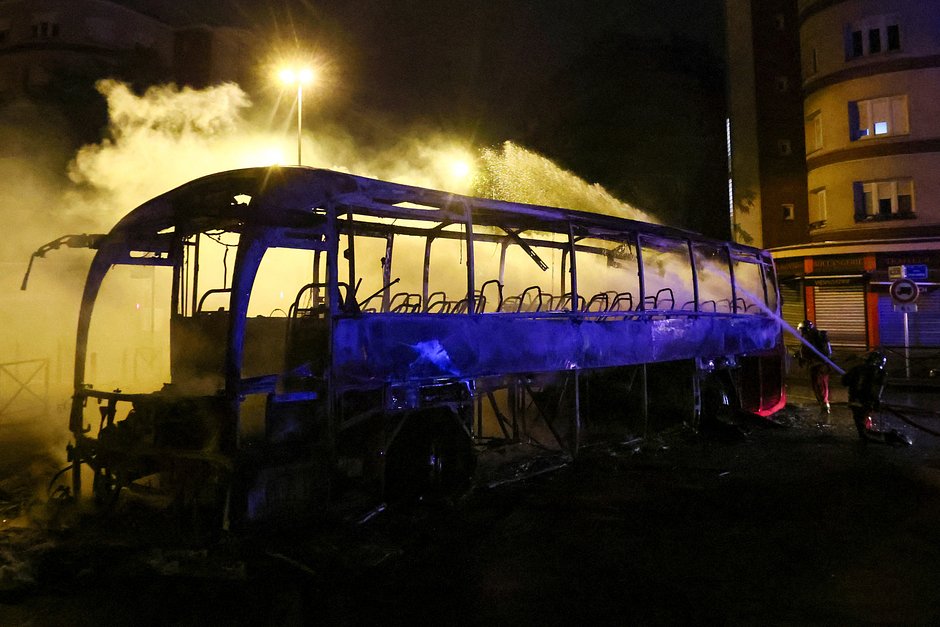 Пожарный заливает сгоревший в ходе протестов автобус водой из шланга, Нантер, Франция, 1 июля 2023 года