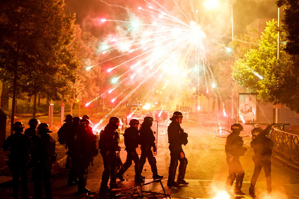 Французские полицейские идут на фоне запущенных демонстрантами фейерверков, Нантер, Франция, 30 июня 2023 года