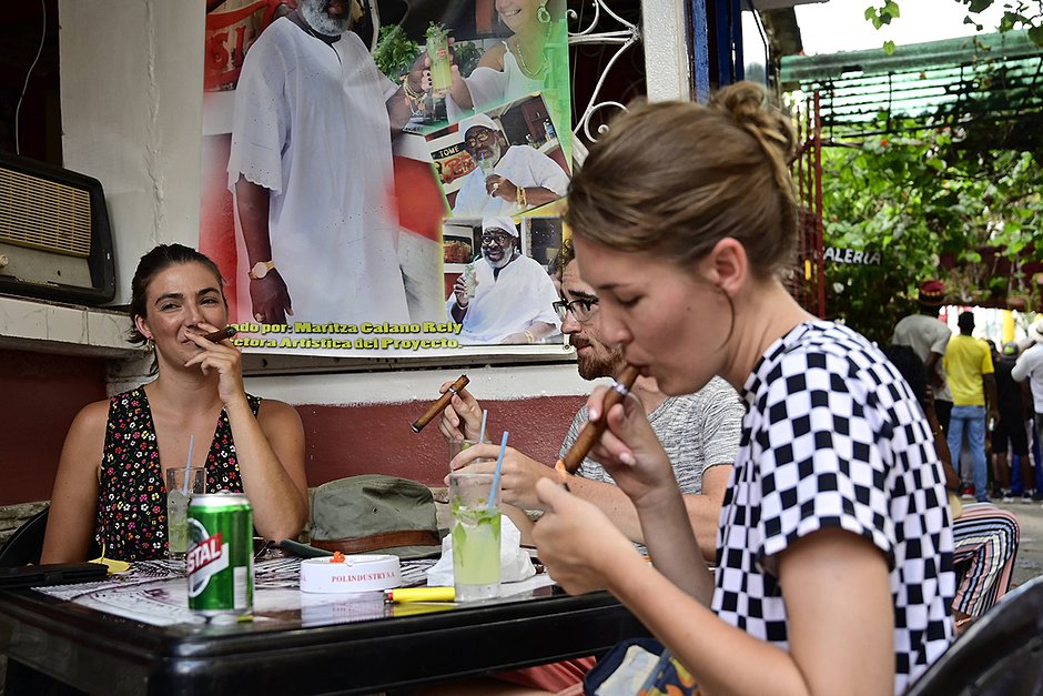 Туристы курят сигары на одной из улиц Гаваны