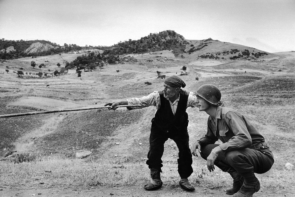 Сицилийский крестьянин показывает военнослужащему из 1-й пехотной дивизии США направление отхода немецких частей в районе Тройны