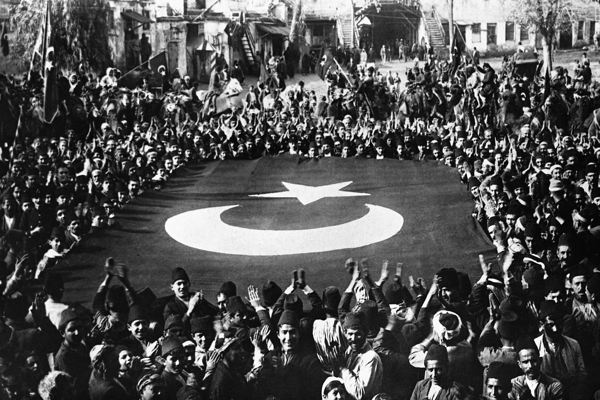 Толпа окружает гигантский турецкий флаг во время празднования ухода оккупационных французских войск из турецкого города Адана, 5 января 1922 года