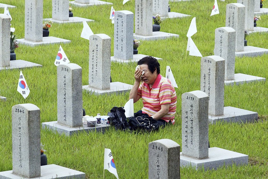 Южнокорейская женщина оплакивает родственника, погибшего в 1950 году в боях корейской войны, на Сеульском национальном кладбище, 6 июня 2004 года
