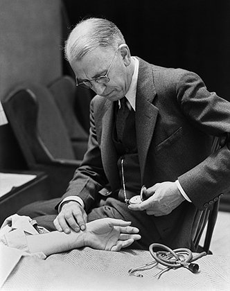Врач, измеряющий пульс пациента с помощью карманных часов, 1930-е годы