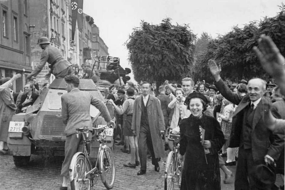 Немецкие жители города Аусиг (ныне Усти-над-Лабем) после аннексии нацистской Германией Судетской области Чехословакии приветствуют германские войска. 9 октября 1938 года. 