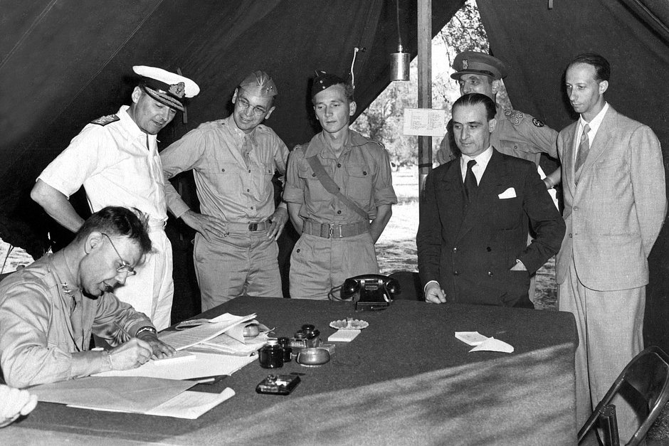 Американский генерал Уолтер Смит ставит подпись под соглашением о перемирии между союзниками и Италией. В штатском стоит итальянский генерал Джузеппе Кастеллано, 3 сентября 1943 года