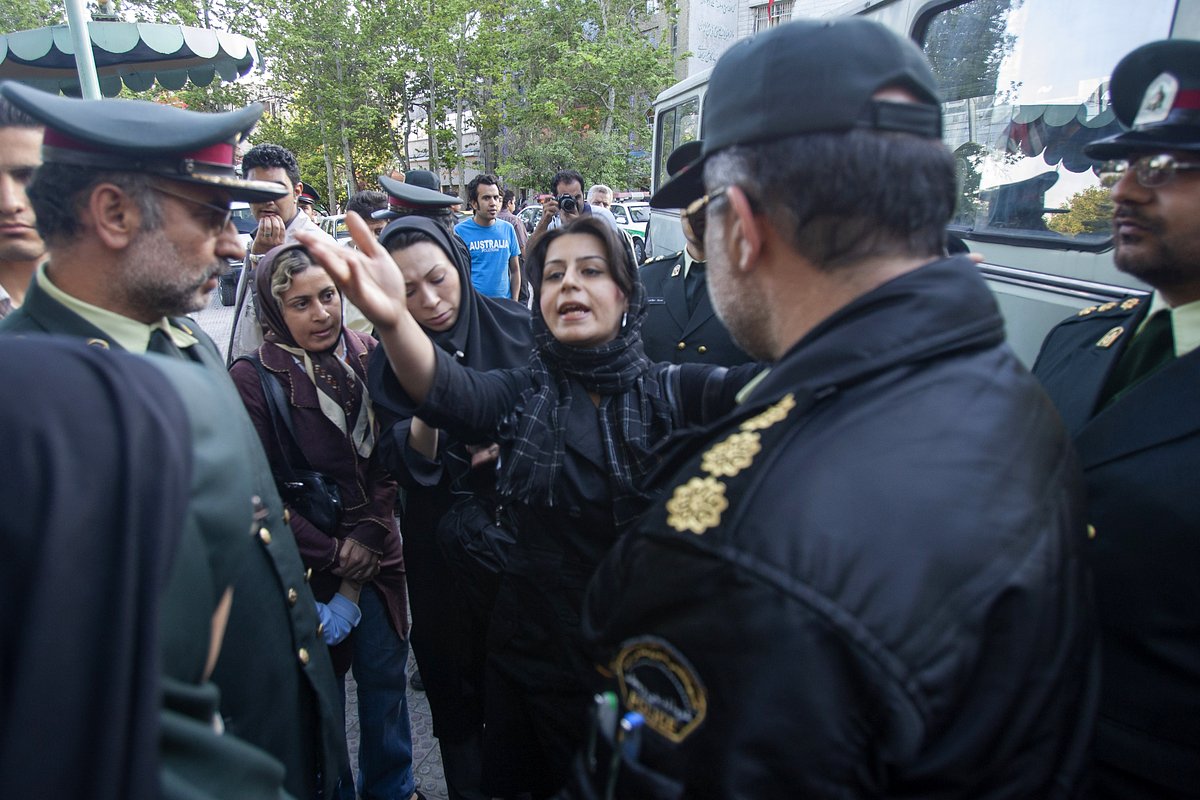 Иранская женщина разговаривает с сотрудниками полиции нравов в Тегеране, 23 апреля 2007 года
