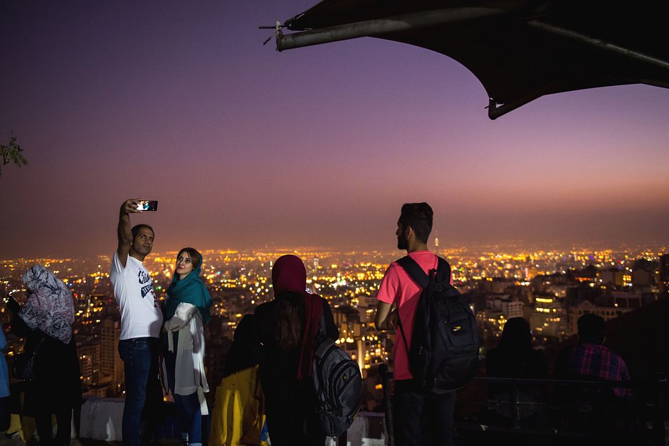 Пара делает селфи на фоне панорамы Тегерана у стены Бам-э, Иран, 20 сентября 2019 года