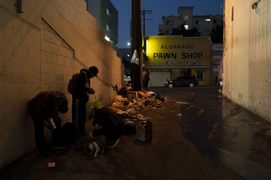 Наркозависимые употребляют фентанил рядом с кучами мусора в переулке. Лос-Анджелес, 23 августа 2022 года