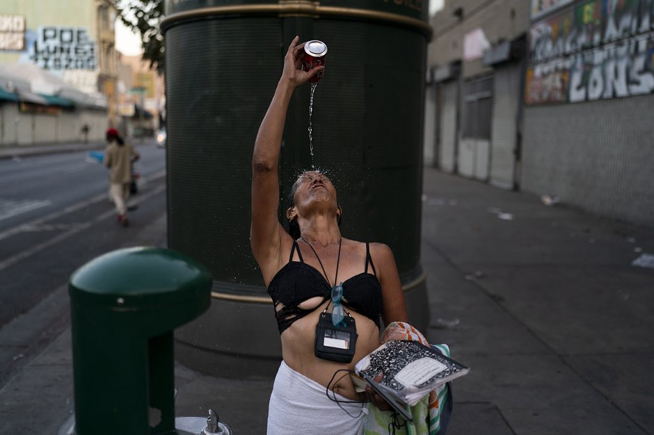 Долорес Флорес, 57-летняя наркозависимая бездомная, умывается с помощью банки из-под газировки, наполненной водой из питьевого фонтанчика. Лос-Анджелес, 21 июля 2022 года