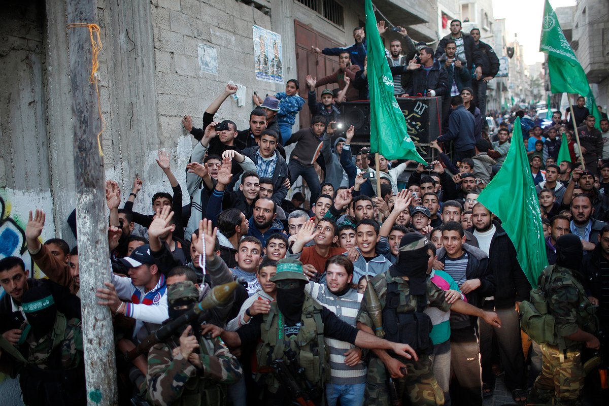 Члены вооруженного крыла движения ХАМАС сдерживают толпу, в то время как глава ХАМАС Халед Мешааль (не на фото) посещает дом семьи Далу, который, по словам свидетелей, был разрушен в результате израильского авиаудара в городе Газа 7 декабря 2012 года. 