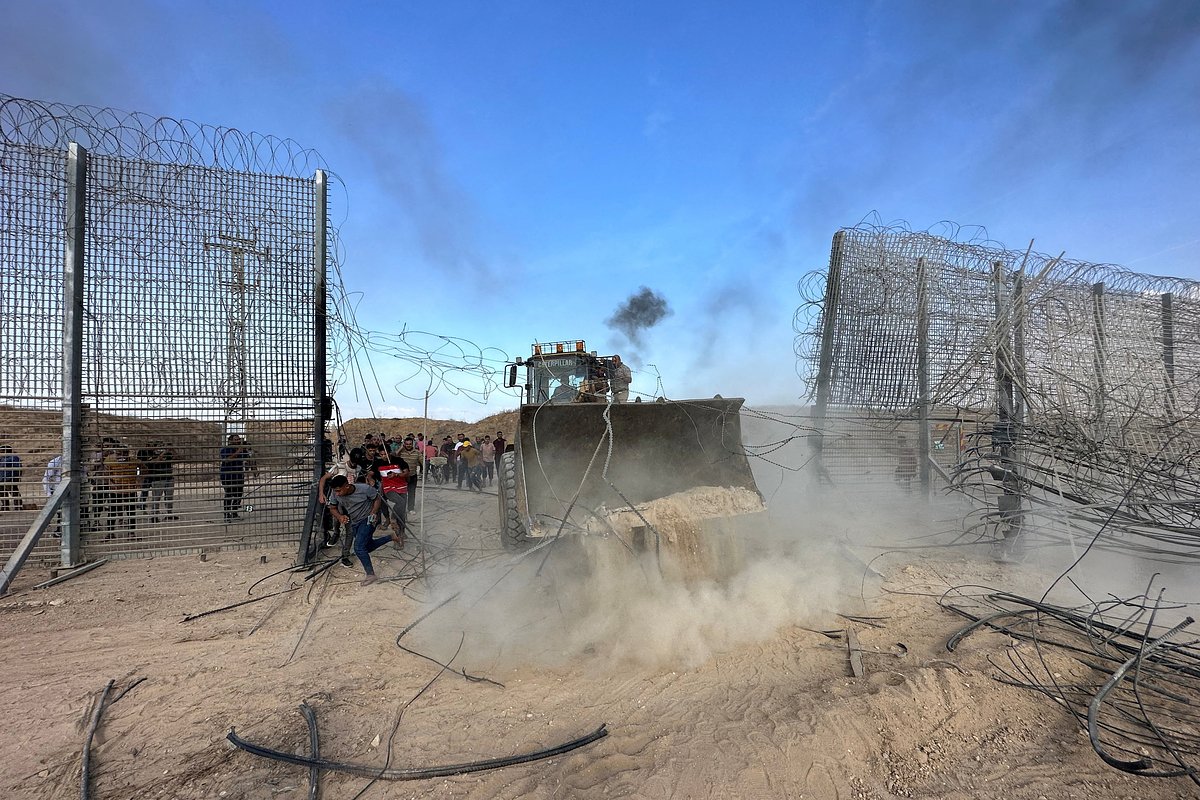 Палестинцы прорываются на израильскую сторону пограничного забора между Израилем и Газой после того, как боевики проникли в районы на юге Израиля. 7 октября 2023 года.