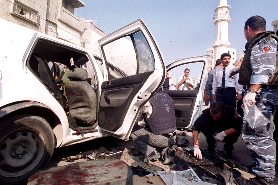 Представители палестинской службы безопасности осматривают автомобиль, в котором был взорван полковник Тайсер Хаттаб, главный помощник главы палестинской разведки, 1 сентября 2001 года, к северу от города Газа