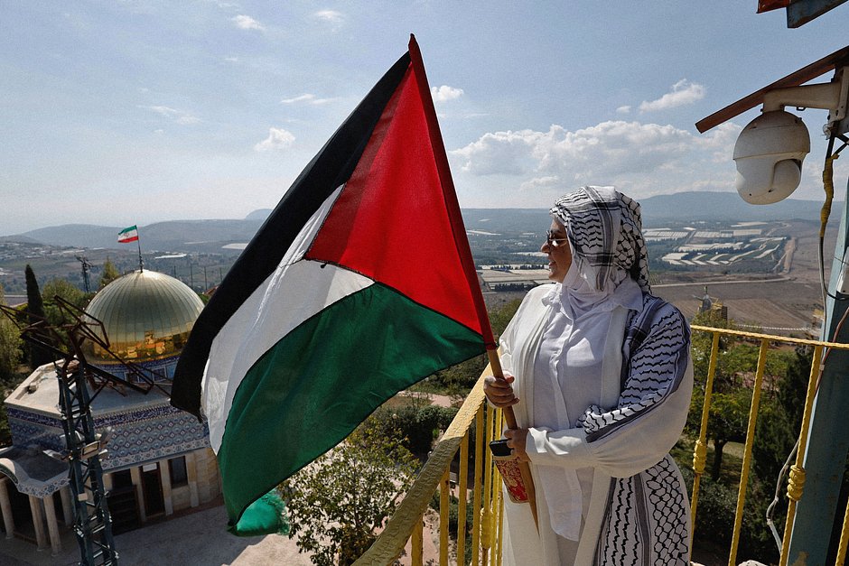 Женщина с палестинским флагом возле точной копии мечети Купол Скалы в туристическом парке «Иранский сад» в деревне Марун ар-Рас недалеко от ливано-израильской границы на юге Ливана, 12 октября 2023 года