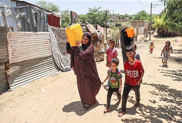 Женщины несут канистры с водой, чтобы принять душ жарким летом в Газе, 14 июля 2023 года