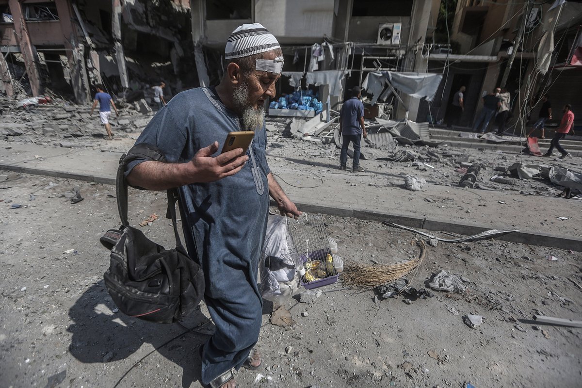 Житель Газы уходит с разрушенной улицы с птичкой в клетке
