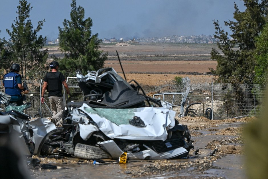 Представители СМИ в кибуце Кфар-Аза идут мимо автомобилей, уничтоженных во время нападения боевиков ХАМАС, Израиль, 10 октября 2023 года