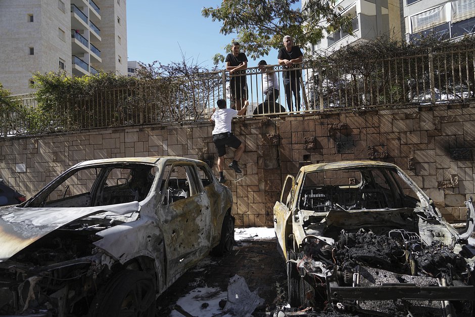 Израильтяне осматривают поврежденные автомобили после попадания в них ракет, выпущенных из сектора Газа, Ашкелон, 13 октября 2023 года