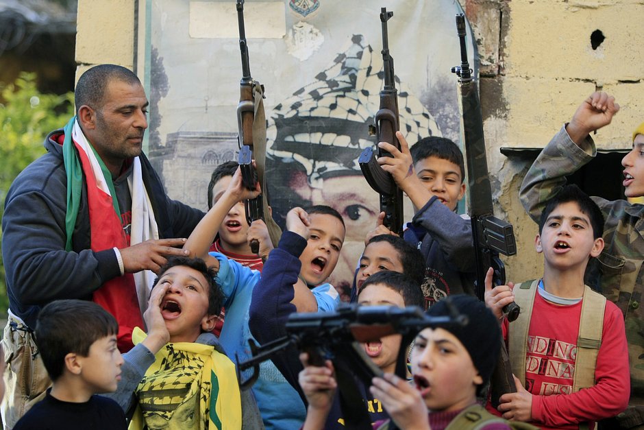 Палестинские дети с оружием в руках празднуют смерть премьер-министра Израиля Ариэля Шарона, лагерь Эйн-эль-Хильве, неподалеку от города Сидон, Ливан, 11 января 2014 года