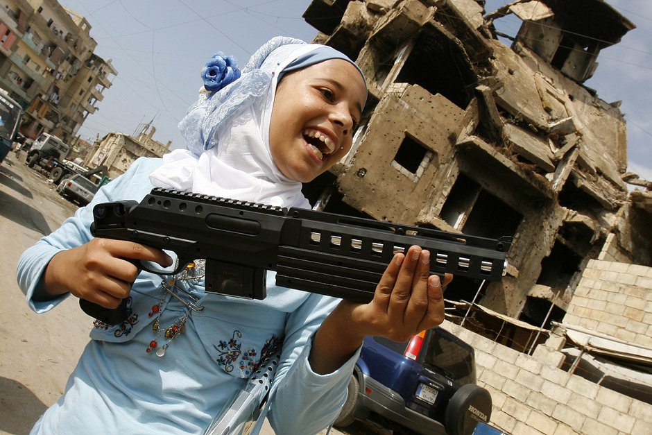 Палестинская девочка играет с игрушечным пистолетом во время празднования Ид аль-Фитр, знаменующего окончание поста в месяц Рамадан, в лагере беженцев Чатила недалеко от Бейрута, Ливан, 12 октября 2007 года