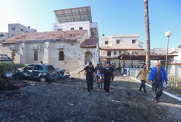 Люди несут жертв обстрела больницы Аль-Ахли