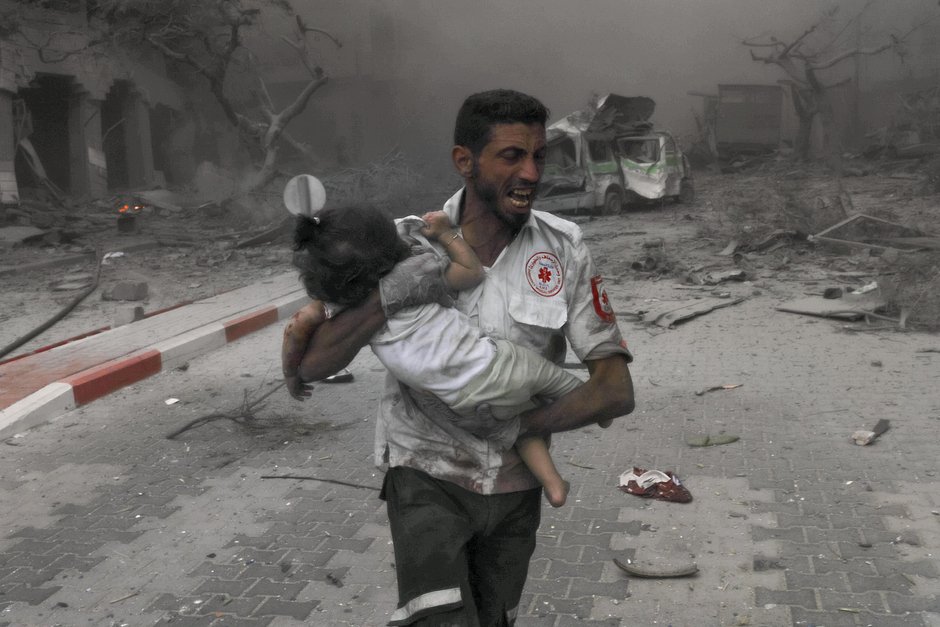 Медицинский работник доставляет пострадавшего ребенка в машину скорой помощи после авиаударов Военно-воздушных сил Израиля, сектор Газа, 9 октября 2023 года