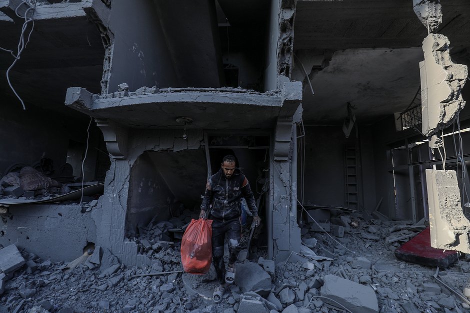 Мужчина выносит свои вещи из дома, разрушенного во время израильских авиаударов в Рафахе, сектор Газа, 18 октября 2023 года