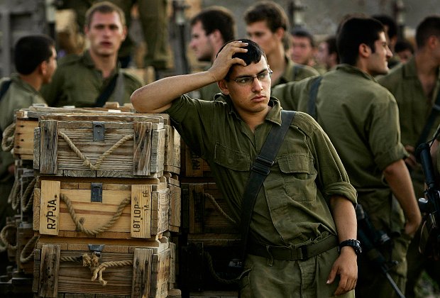 Солдат ЦАХАЛ отдыхает возле коробок с боеприпасами на границе Израиля и Ливана