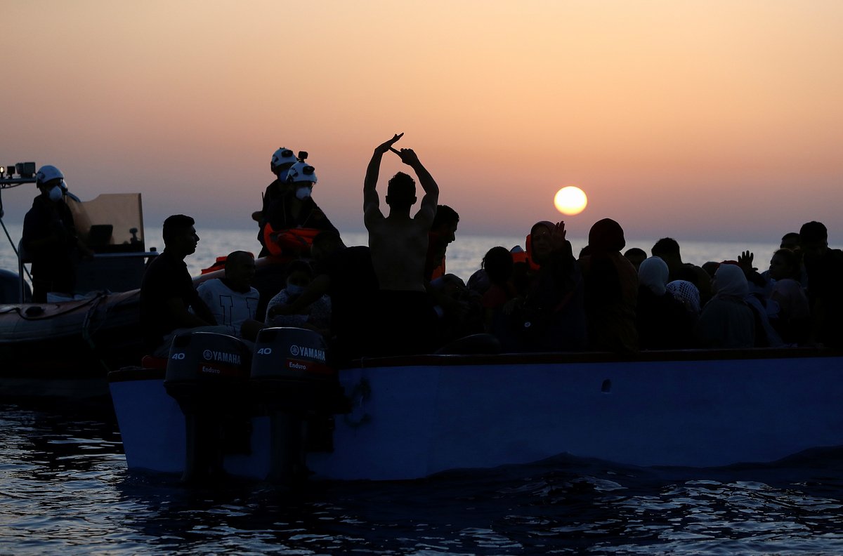 Члены экипажа спасательного корабля Sea-Watch 3 раздают жилеты мигрантам во время операции в международных водах у побережья Ливии, в западной части Средиземного моря, 30 июля 2021 года