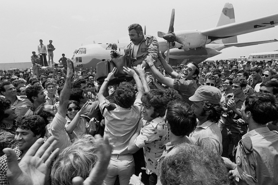 Толпа в аэропорту Тель-Авива поднимает командира эскадрильи спасательных самолетов, вернувшихся в Израиль после проведения операции в аэропорту Энтеббе в Уганде 3 июля 1976 года