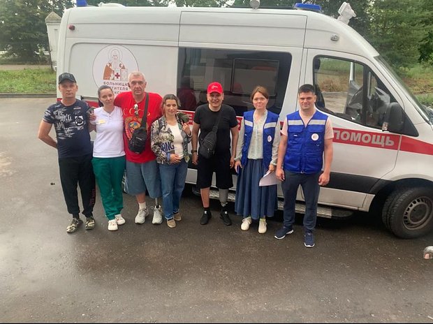 Сотрудники и пациенты больницы Святителя Алексия возле больничной скорой помощи, которая перевозит людей из зоны СВО в Москву и обратно