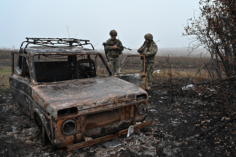 Ukrainian servicemen inspect a destroyed vehicle outside the village of Robotyne