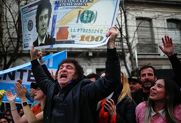 Хавьер Милей держит плакат в виде 100-долларовой банкноты с изображением своего лица во время предвыборной кампании, сентябрь 2023 года