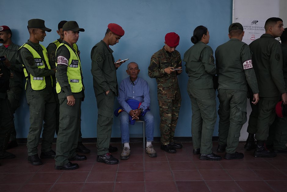 Солдаты и гражданские лица стоят в очереди, чтобы проголосовать на референдуме о будущем спорной территории с Гайаной, на избирательном участке в Каракасе