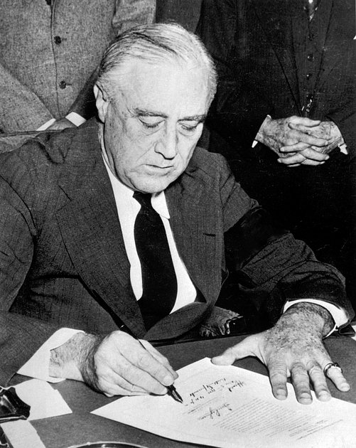 Президент США Франклин Рузвельт после атаки японцев на Перл-Харбор подписывает декларацию об объявлении войны Японии, 8 декабря 1941 года