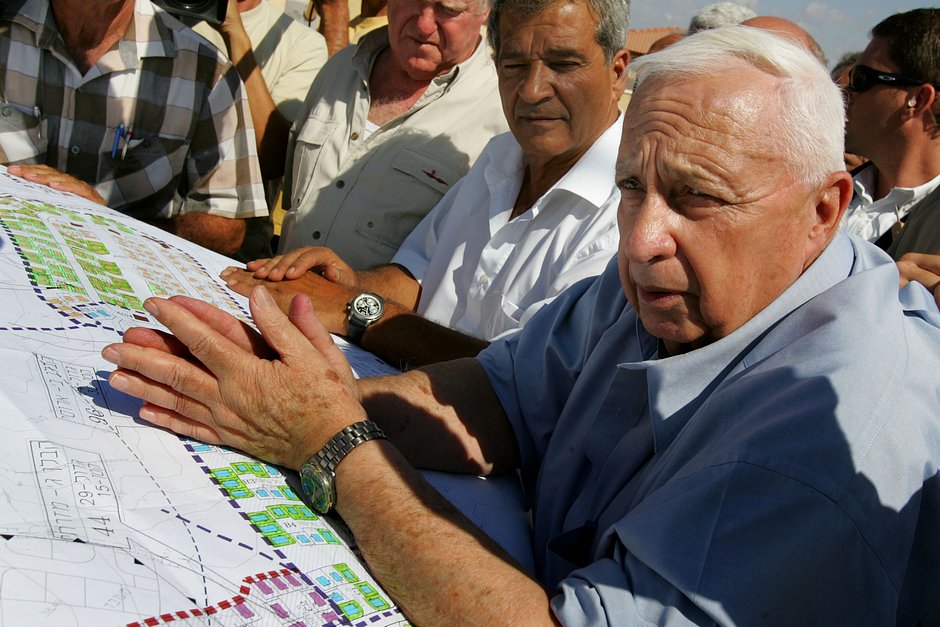 Премьер-министр Израиля Ариэль Шарон с планами строительства временных домов для поселенцев, которые должны быть эвакуированы из сектора Газа. Строительная площадка Ницаним на юге Израиля, 5 июля 2005 года